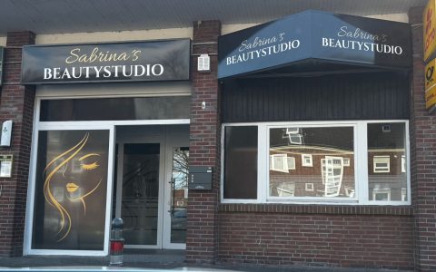Beautystudio mit Schaufenster und schwarzem Schriftzug in einer städtischen Umgebung.